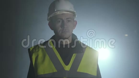 建筑工人制服上的工程师的肖像和工作场所聚光灯下黑色背景上的头盔视频的预览图