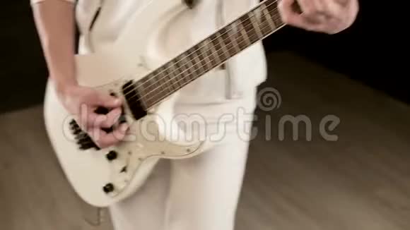 特写时尚的节奏吉他手不同的眼睛穿着白色衣服黑色背景富有表现力地演奏视频的预览图