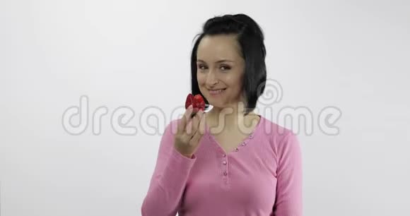 年轻的美女白色背景下吃着又大又新鲜又多汁的草莓视频的预览图