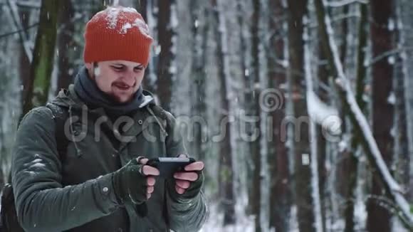 一个人在雪地森林里用手机社交网络看视频下注笑和高兴微笑面对视频的预览图
