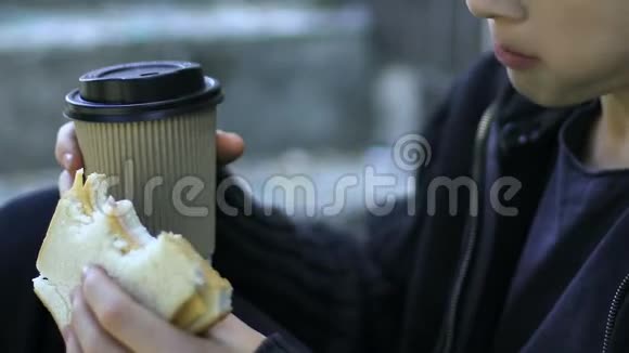 无家可归的男孩在户外吃三明治和喝咖啡贫穷特写视频的预览图