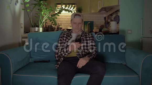 快乐男人坐在沙发上用手机玩游戏4K视频的预览图
