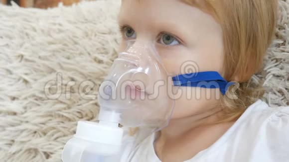 小女孩在家里用雾化器吸入并看电视儿童哮喘吸入雾化器蒸汽视频的预览图