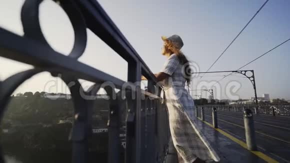 戴帽子穿衣服的女士站在桥上看日出视频的预览图