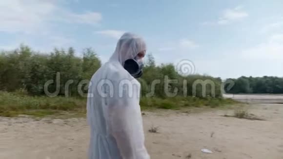 穿着防护服和呼吸器的人正站在一条干河旁边的海滩上视频的预览图