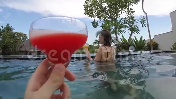 年轻可爱的一对夫妇在热带度假别墅的游泳池里碰杯视频的预览图
