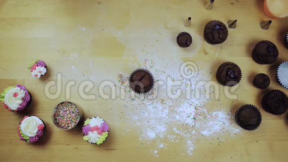 女性手装饰巧克力纸杯蛋糕的俯视图年轻女人用糕点包做彩色奶油视频的预览图