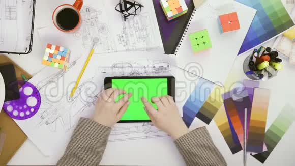 双手顶视女设计师使用她的平板电脑桌子上有绿色屏幕滚动新闻照片视频的预览图