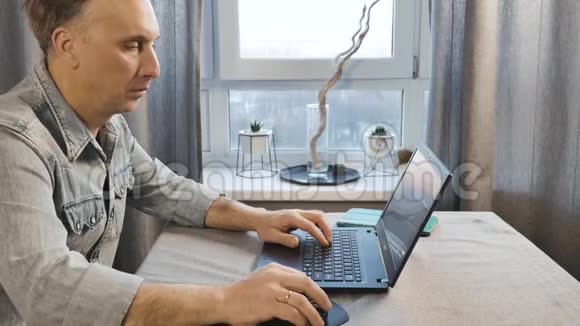 一个在笔记本电脑上工作的中年人自由职业者在家工作侧视图视频的预览图