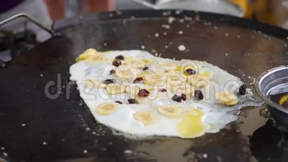 鸡蛋与香蕉和葡萄干在平底锅在夜市炒街头美食4k视频的预览图