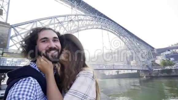 一对情侣在桥附近的堤岸上自拍视频的预览图