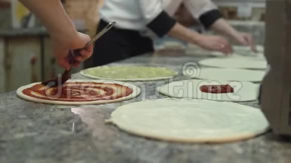 一组厨师把番茄酱均匀地放在披萨面团圈上视频的预览图