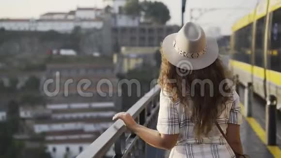 戴帽子的漂亮女人在桥上散步视频的预览图
