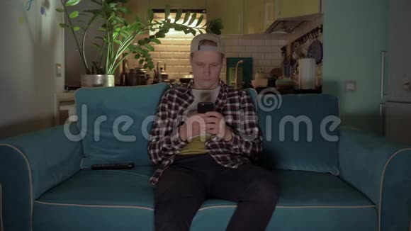 快乐的人坐在沙发上用手机玩游戏4K视频的预览图