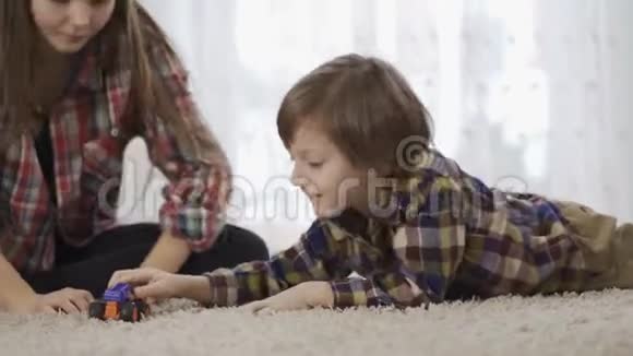 肖像姐姐和弟弟一起玩坐在地板上毛茸茸的地毯上爱的家庭视频的预览图