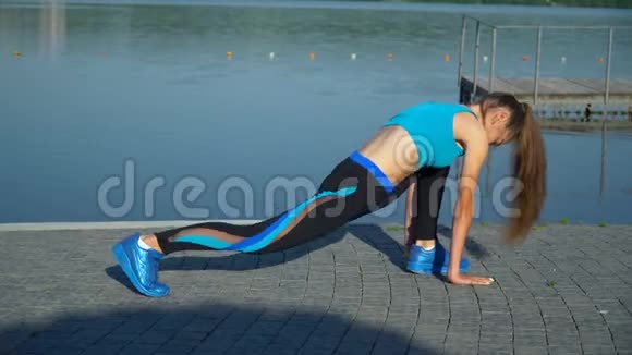 年轻女子穿着运动服夏天在湖岸上蹲着视频的预览图
