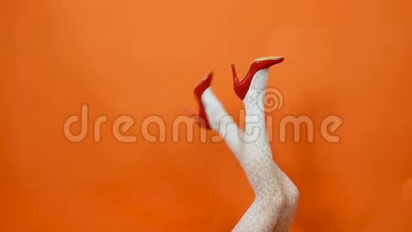 女人有长腿鱼网白色长袜在橙色背景在工作室复古风格视频的预览图