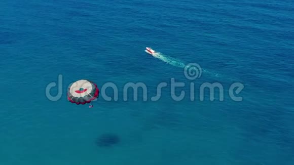 鸟瞰图人们乘着由摩托艇牵引的彩色降落伞飞行在蓝天下飘扬视频的预览图