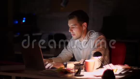 高加索人在电脑上打字的录像使用键盘和耳机跳舞而坐得很晚视频的预览图