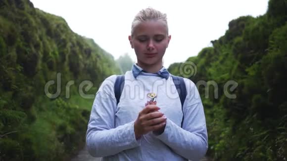 神秘的女孩站在风景优美的道路上带着一朵花视频的预览图