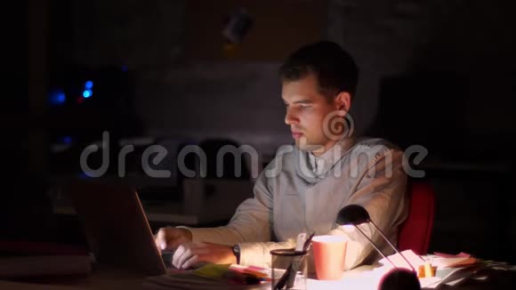 精力充沛的现代白种人商人正在电脑键盘上打字而坐在室内黑暗的背景迟到视频的预览图