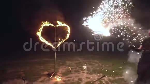 火秀男艺术家将手中的火物用燃烧的心在背景下扭曲视频的预览图