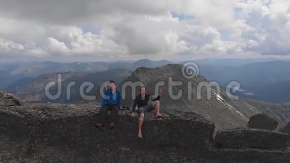 两个勇敢的男人朋友坐在山顶上的惊人自拍在无人机上拍摄视频的预览图