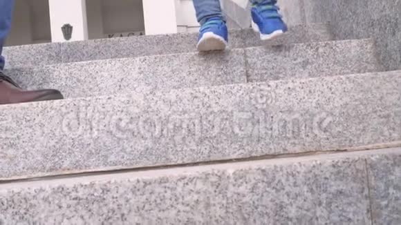 在城市公园里一个男孩穿着蓝色运动鞋和牛仔裤一步一步地走下花岗岩梯视频的预览图