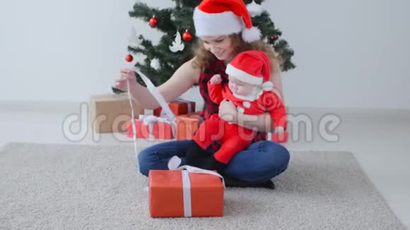 家庭假日和圣诞节的概念年轻的母亲带着孩子打开圣诞礼物视频的预览图