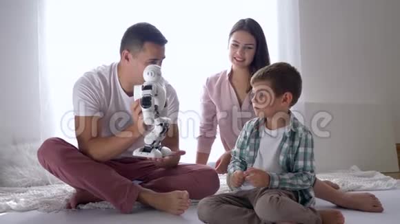现代礼物父母送给坐在地上遥控智能手机的小儿子智能机器人玩具视频的预览图