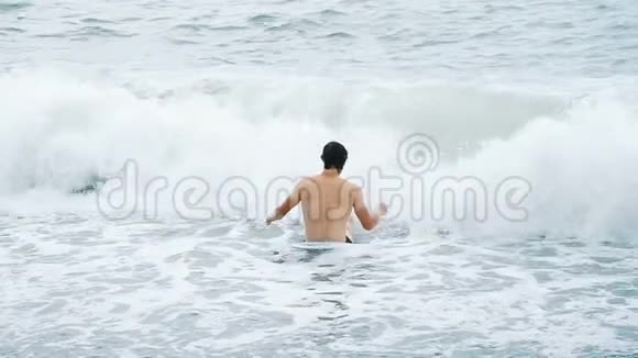 海浪覆盖着一个沐浴在风暴中的快乐男人视频的预览图