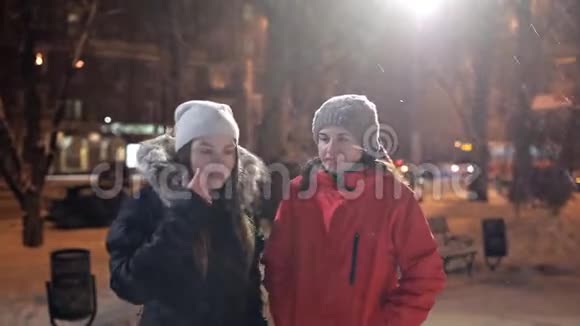 冬天的天气两个年轻女孩在傍晚的城市散步视频的预览图