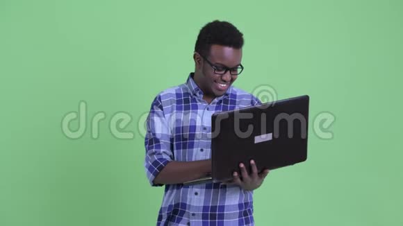 快乐的年轻非洲时髦男人一边思考一边用笔记本电脑视频的预览图