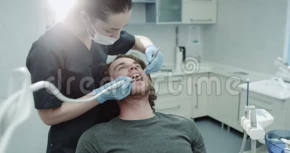 一个女牙医的肖像和她的病人魅力男在牙科室有口腔卫生程序视频的预览图