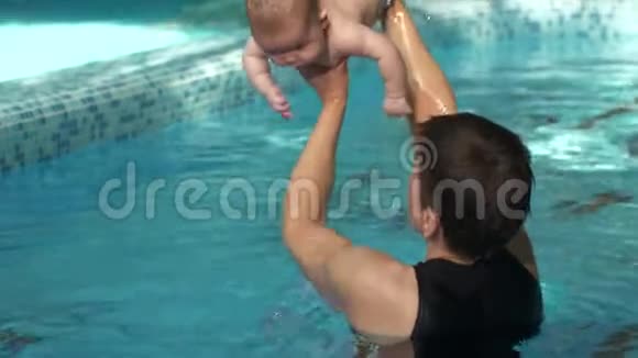 带着教练在游泳池里做运动的孩子视频的预览图