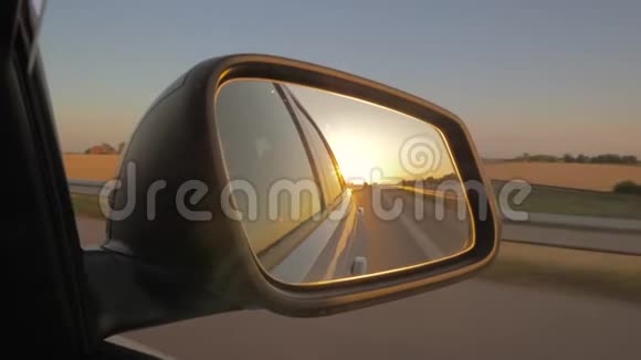 日落时侧视车镜的特写视频的预览图