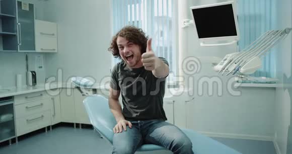 非常有魅力的年轻病人在牙科诊所里坐在牙列椅上检查牙齿后非常高兴视频的预览图