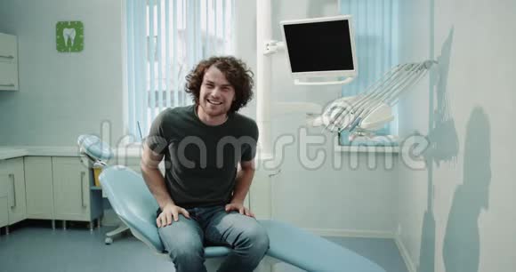 牙科医生检查后微笑的病人坐在一张蓝色的牙医椅上在镜头前露出一个很大的样子视频的预览图