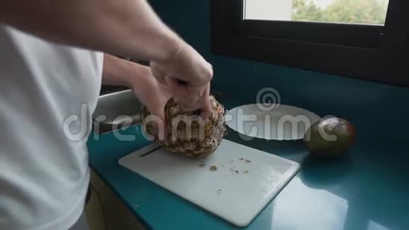 男人正在厨房用刀子切菠萝视频的预览图