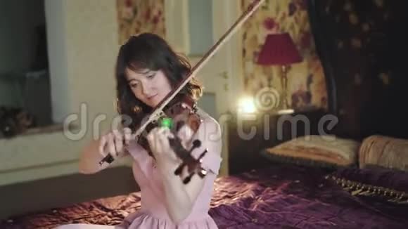 独自演奏乐器专业小提琴手坐在床上演奏视频的预览图