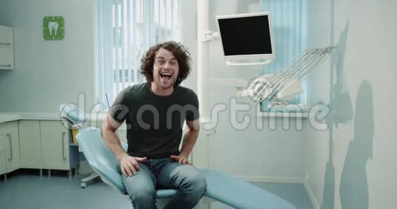 非常棒的家伙带着大大的微笑在一家诊所里看牙医等待他的牙齿检查坐在上面视频的预览图