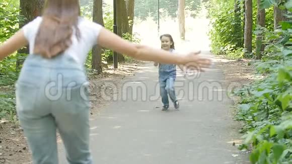家庭观念可爱的女婴跑到妈妈的怀抱在公园里视频的预览图