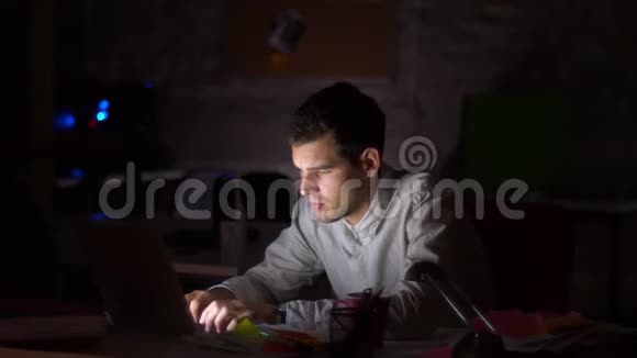 集中的白种人男性正在看电脑屏幕和键盘打字在桌面工作深夜黑暗视频的预览图