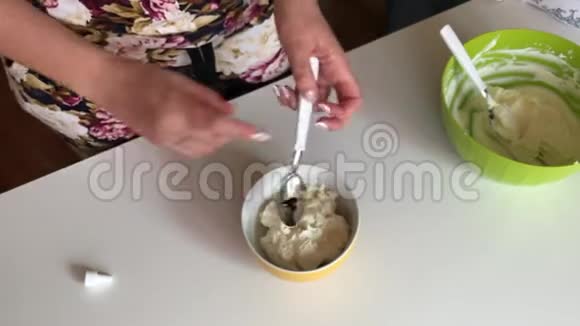 女人用勺子混合软奶酪为蛋糕准备奶油添加了食用色素视频的预览图