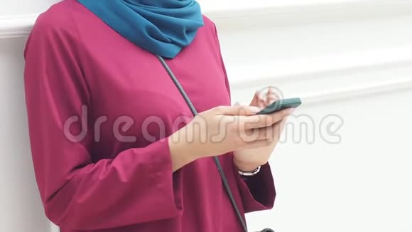 戴头巾的穆斯林女孩使用智能手机进行网上购物视频的预览图