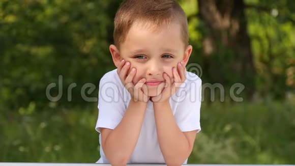 一个孩子的脸特写快乐的宝宝在绿色森林的镜头前微笑视频的预览图