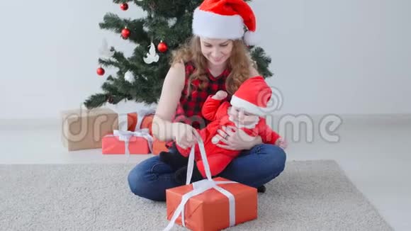 家庭假日和圣诞节的概念年轻的母亲带着孩子打开圣诞礼物视频的预览图