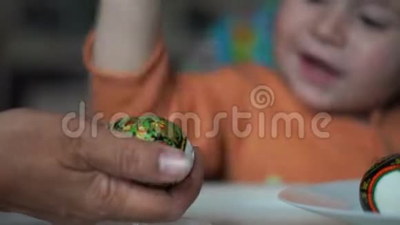 可爱的小男孩用妈妈的手打鸡蛋视频的预览图