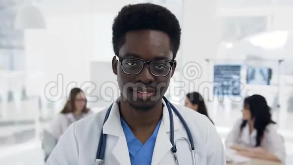 自信的非洲男性医生的肖像而科克团队在医院工作的背景视频的预览图
