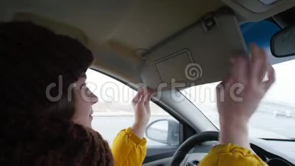 一个穿着黄色夹克的年轻女子坐在司机座位上放下面罩照镜子视频的预览图